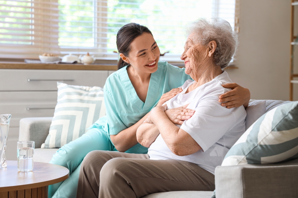 Physical,therapist,hugging,senior,woman,on,sofa,at,home